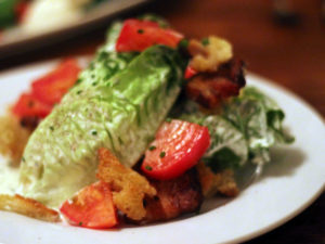 Salad of baby romaine, pork belly, pickled tomatoes and torn croutons. Intentional. Authentic.