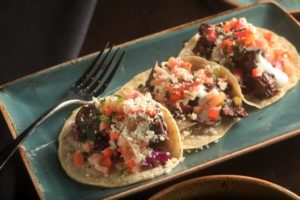 Oso Restaurant's "Mole Braised Lamb Tacos" include cabbage, creme fraiche, pickled vegetable salsa and cotija.