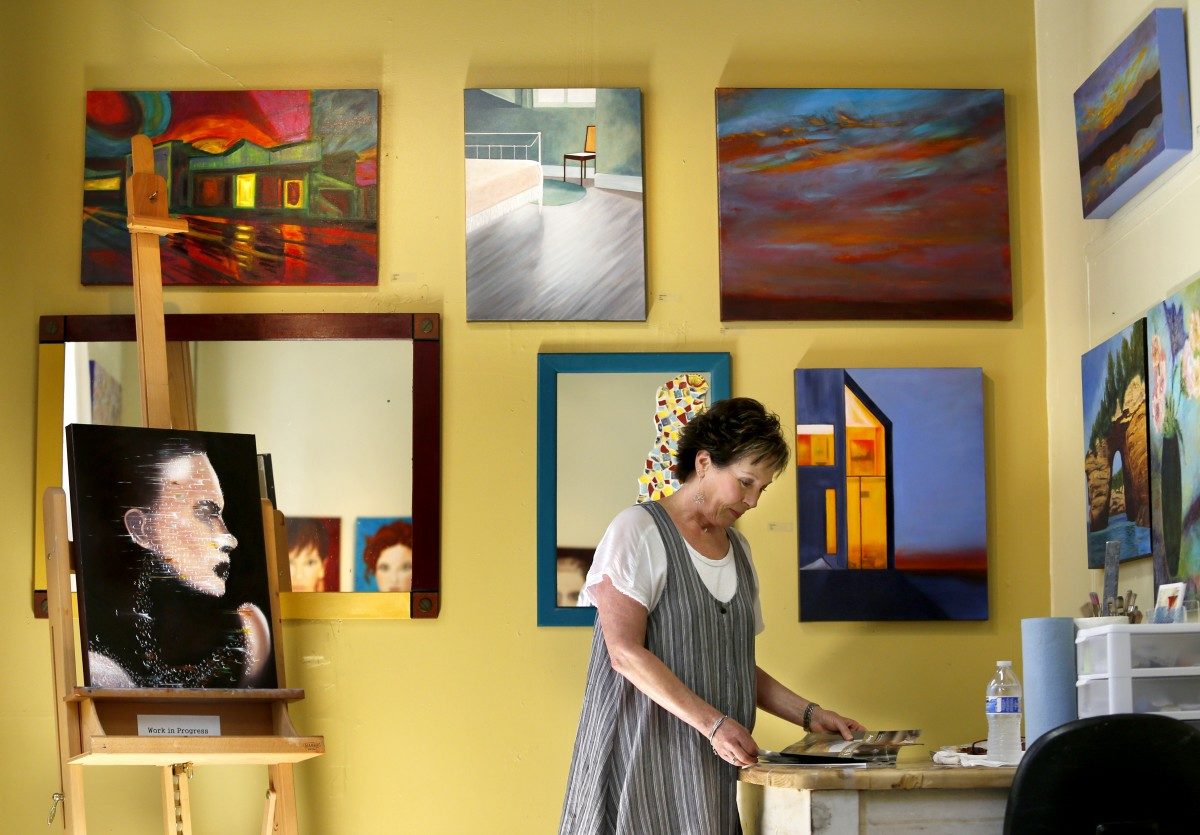 Artist Taunee Callahan flips through a magazine as she waits for people to visit her gallery during the SOFA Artwalk in Santa Rosa. (Beth Schlanker/The Press Democrat)