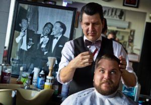 The 50's are back in style at the Santa Rosa Barber Shop. Owner Eric Gardea runs pomade through the hair of Cody Garzini. (JOHN BURGESS / The Press Democrat)