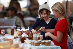 Gwyneth Barker, 7, left, and Amber Vanoni, 8, taste honey from the Beelove Honey during the West End Farmers Market in Santa Rosa. (Beth Schlanker / The Press Democrat) 