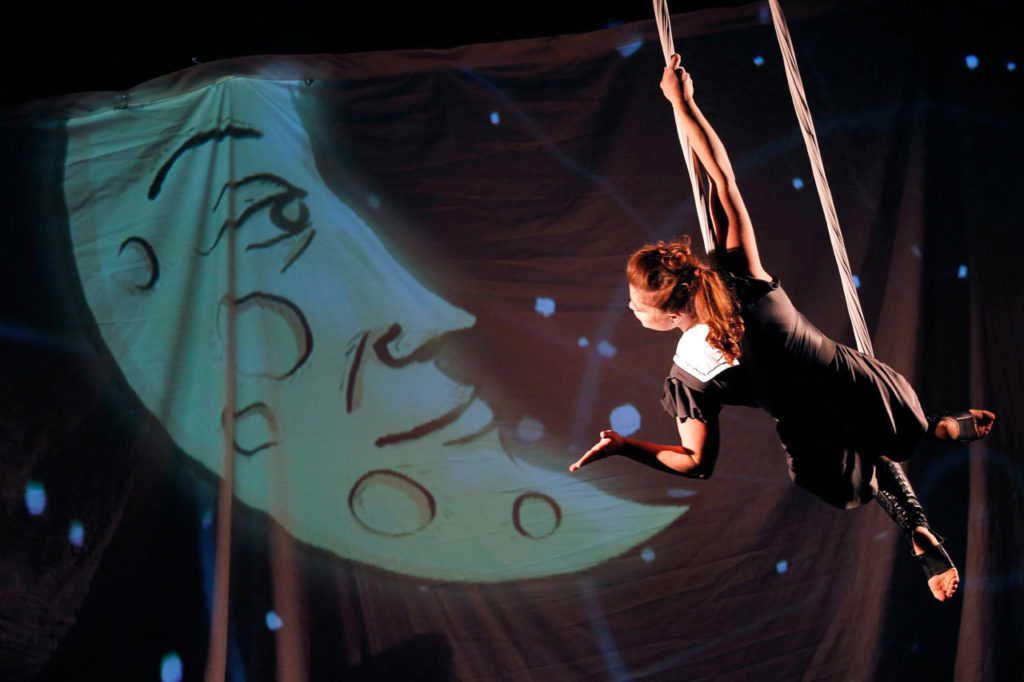 Aerialist Abigail Baird blows a kiss to the moon while performing on a silk with an animated movie playing on a screen behind her during Le Cirque de Boheme at Cornerstone Sonoma. (Alvin Jornada / The Press Democrat)