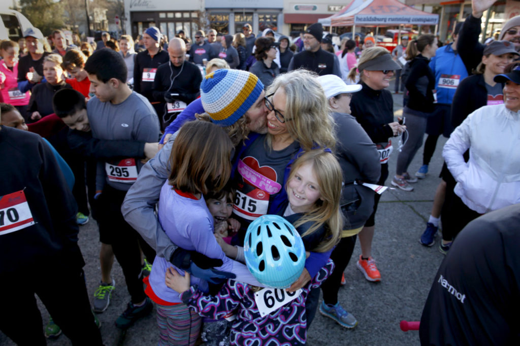 Jeremy Bardell, top, gives his girlfriend Tamara Rocco a kiss during a pre-run hug with family members Claire Bardell, right, Grace Rocco, center, and Maiya Bardell, left, during the Love Run in Healdsburg, on Saturday, February 11, 2017. (BETH SCHLANKER/ The Press Democrat)