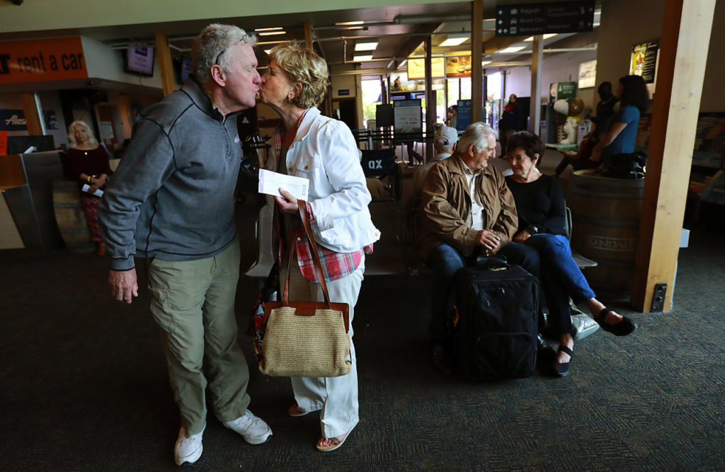 From left, Jim Nichole kisses his wife Nickie goodbye as she travels to see a grandchild graduate while Lou and Dena Pelfini wait to board their flight to Phoenix at the Charles M. Schulz Sonoma County Airport on Wednesday, May 24, 2017. (John Burgess/The Press Democrat)