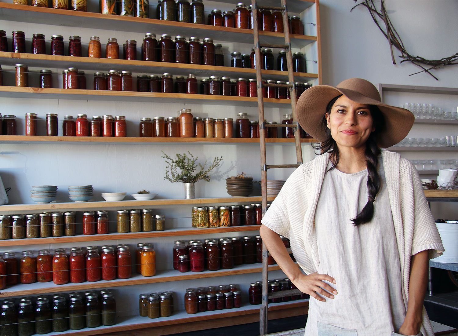 Dalia Martinez of Flower and Bone in front of their wall of preserves. Heather Irwin/PD