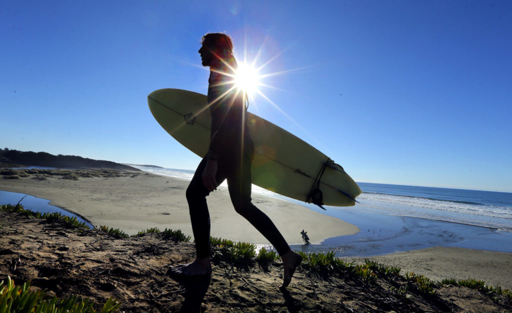 Andre North of Occidental head back to the car after a day of good waves at Salmon Creek State Beach in Bodega Bay on Thursday. (JOHN BURGESS / The Press Democrat)