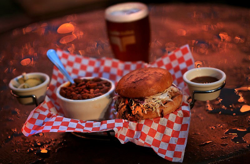 The pulled pork sandwich with beans as a side with a glass of HopMonk Tavern Al at the Twin Oaks Road House in Penngrove. (Kent Porter / The Press Democrat)