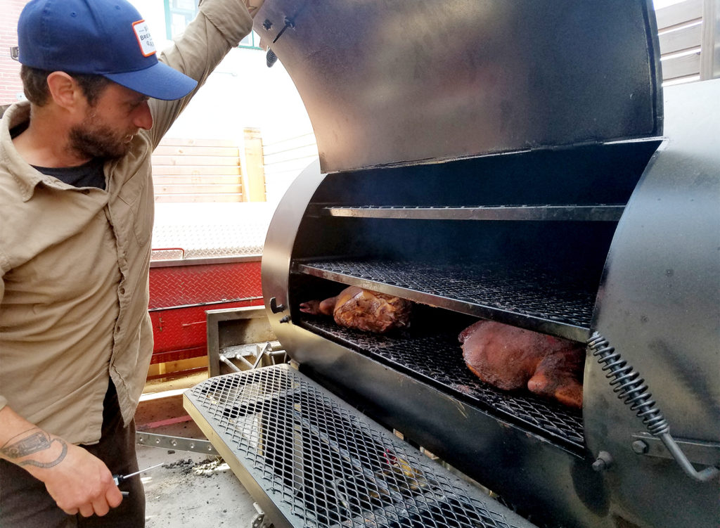 Chef CHRIS BEERMAN checking barbecued pork at Brewster’s Beer Garden in Petaluma. Heather Irwin/PD