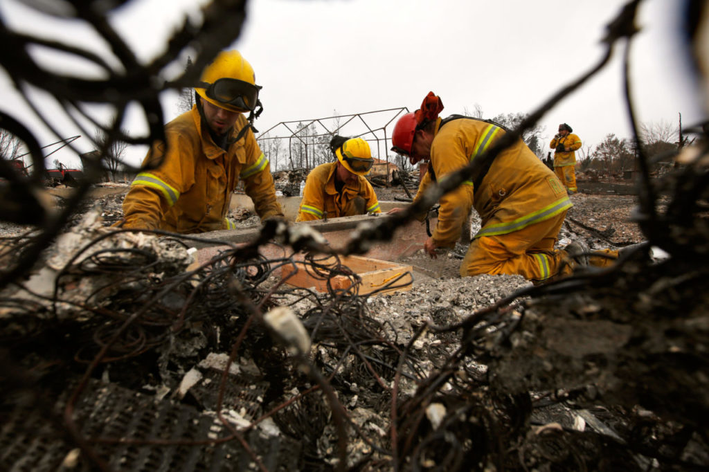 Rancho Adobe Fire Protection District engineer Robert Nappi, left, engineer Morgan De Jong, and captain Tim Caldwell sift through the remains of Nappi's home in the Coffey Park neighborhood, which was destroyed by the Tubbs Fire while Nappi and his colleagues were out battling the fire in other parts of Sonoma County, in Santa Rosa, California, on Thursday, October 19, 2017. (Photo by Alvin Jornada)