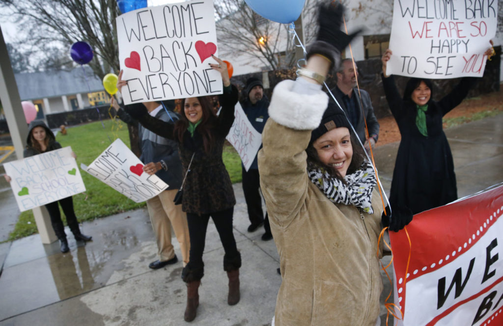 Gina Unciano joins with a group of employees from Redwood Credit Union including Kimberly Williams, left, and Mishel Kaufman, right, to welcome students as they return to Riebli Elementary School on Monday, January 8, 2018 in Santa Rosa, California . The school was closed for three months after the Tubbs fire in October. (BETH SCHLANKER/The Press Democrat)