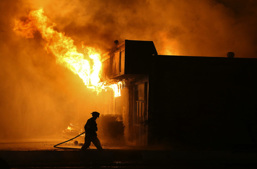 A firefighter works on controlling the blaze at Schmidt Firearms & Accessories, in Santa Rosa on Monday, October 9, 2017. (Christopher Chung/ The Press Democrat)