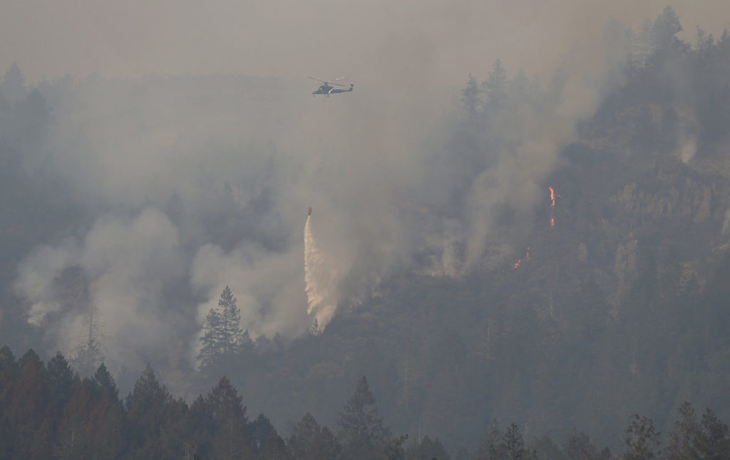 A helicopter drops water on the fire in the area of Hood Mountain Regional Park, near Pythian Road, in Santa Rosa on Monday, October 16, 2017. (Christopher Chung/ The Press Democrat)