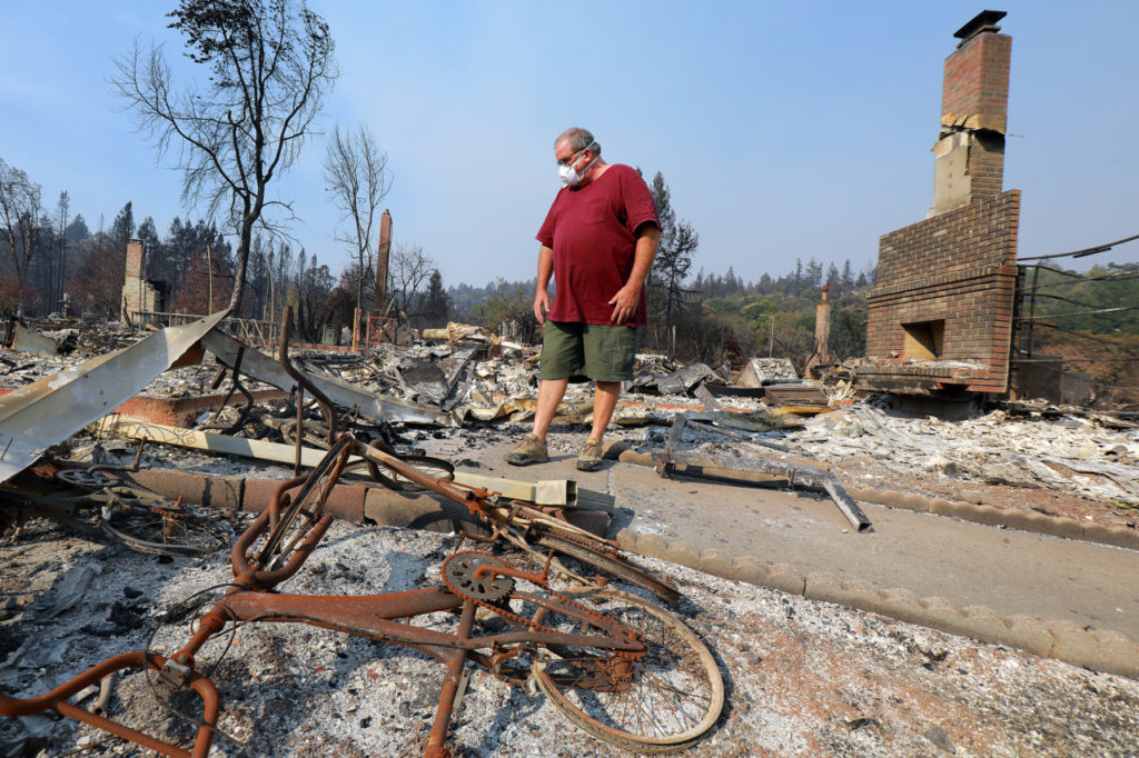 Larry Broderick looks through the rubble of his former home with the remains of his children's bikes in the foreground in the Parker Hill neighborhood of Santa Rosa on October 13, 2017. (photo by John Burgess/The Press Democrat)