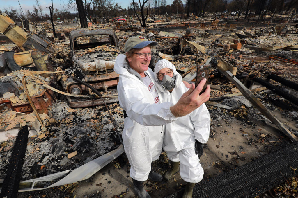 Before starting the long task of sifting through the ashes of their burned out home on San Miguel Rd., Paul and Susan Donner pose for a selfie on the first day residents could return to their homes in the Coffey Park neighborhood of Santa Rosa. (Photo by John Burgess)