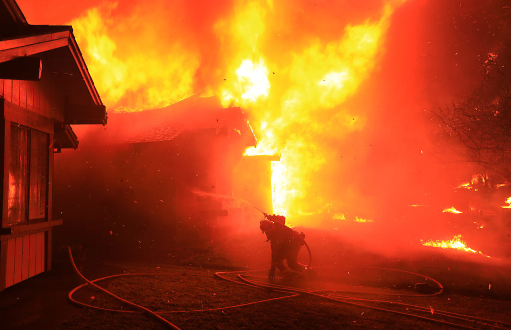 A Cazadero firefighter struggles to protect a home from catching fire in Coffey Park, Monday Oct. 9, 2017 in Santa Rosa. (Kent Porter / The Press Democrat)