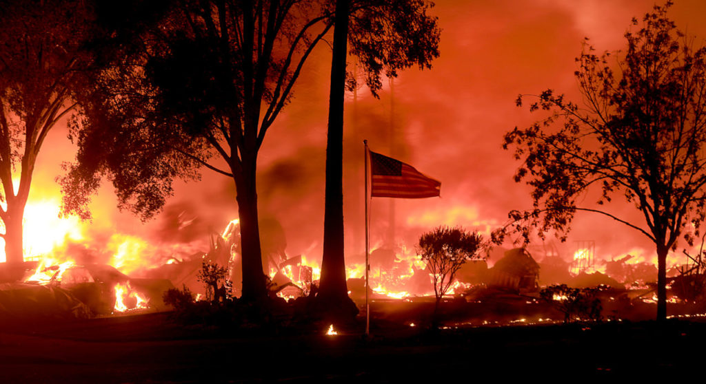An American flag still fly's as as structures burn in Coffey Park, Monday Oct. 9, 2017. (Kent Porter / The Press Democrat)