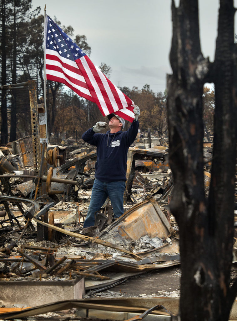 Jason Miller unfurls the American flag he flies over the remains of his Jenna Place home on the first day residents could return to their homes in the Coffey Park neighborhood of Santa Rosa. (Photo by John Burgess)