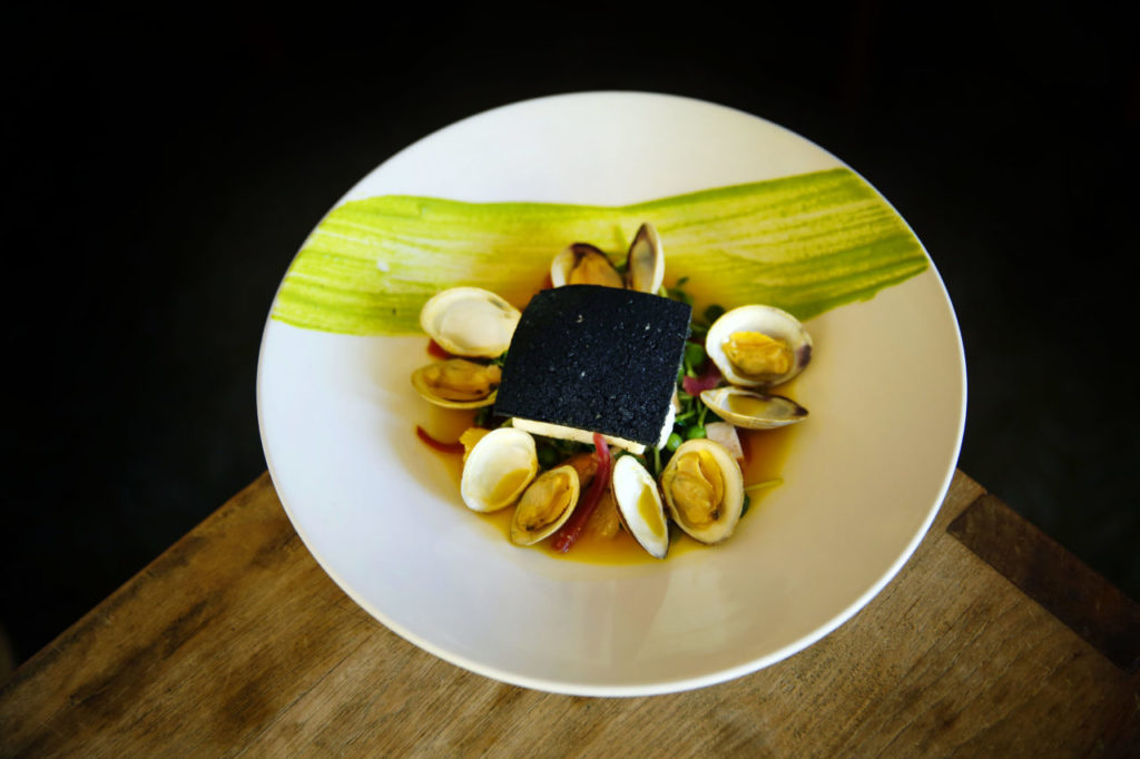Alaskan halibut with cuttlefish ink crust, sturgeon 'bacon,' saffron steamed muscles and english pea fondue is served at Dry Creek Kitchen in Healdsburg on Wednesday, May 28, 2014. (Conner Jay/The Press Democrat)