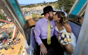 Logan and Brittany Heilman of Santa Rosa seal their marriage with a kiss after exchanging vows on the Century Wheel at the Sonoma County Fair, Friday August 11, 2017. (Kent Porter / Press Democrat) 2017