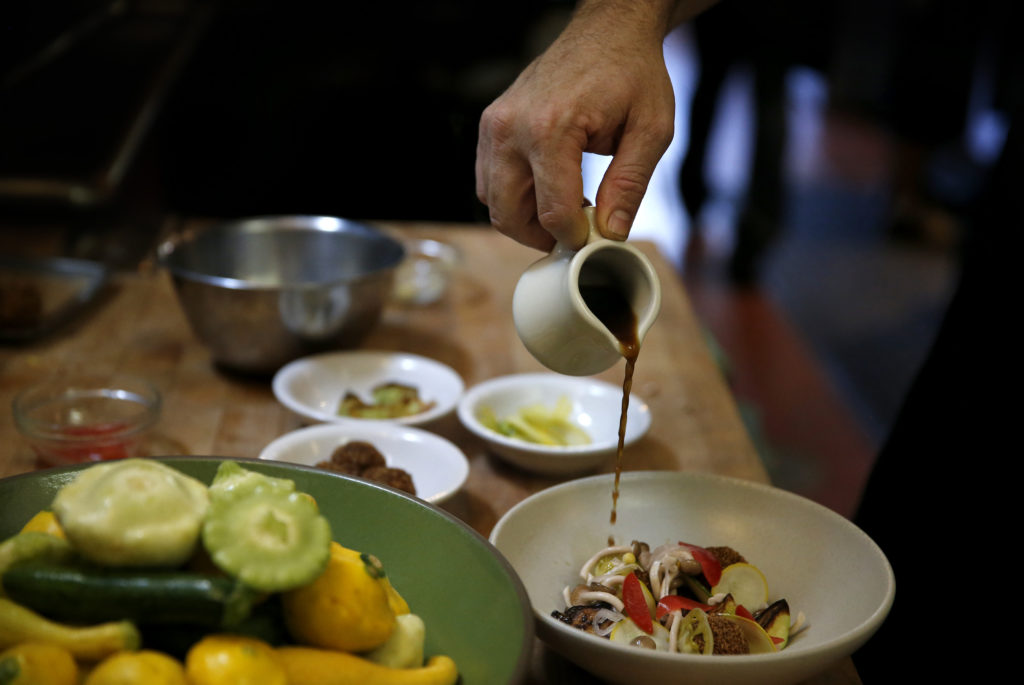 Chef Joe Zobel pours a a mushroom broth over a dish of squash "meatballs", squash crudo and pickled summer vegetables at Peter Lowell's Restaurant in Sebastopol, on Wednesday, July 20, 2016. (BETH SCHLANKER/ The Press Democrat)
