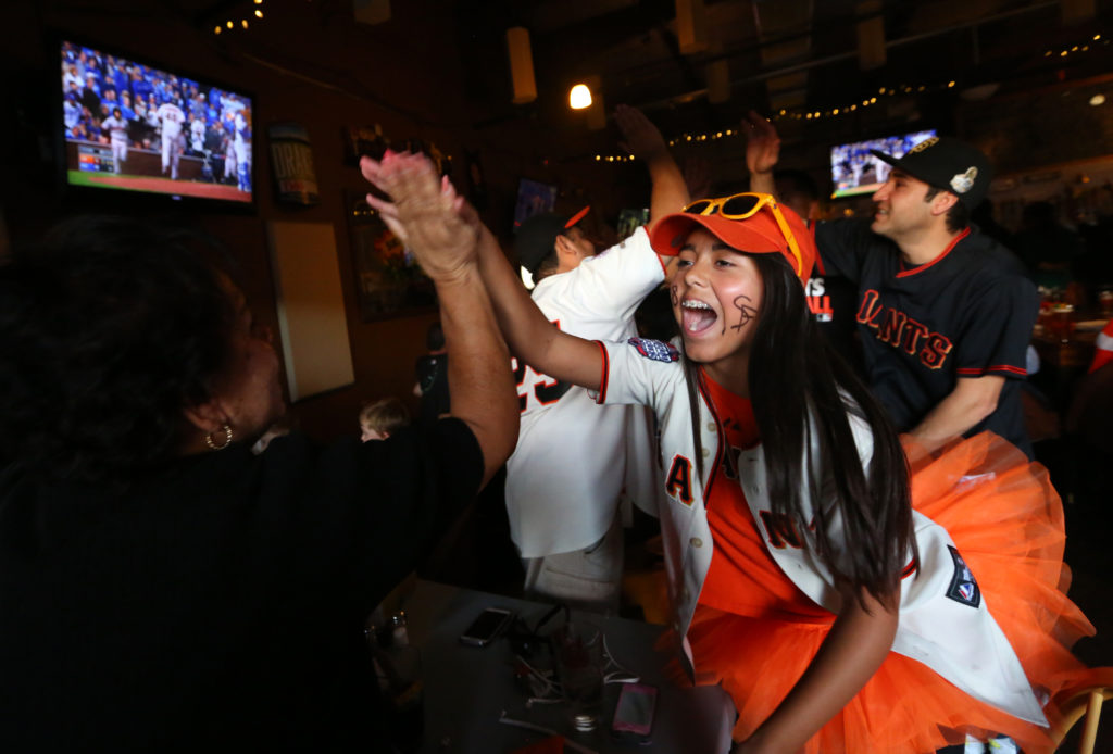 Rylie Lopez, right, 13, high-fives her grandma Rita Lopez after watching the Giants score a run during the final game of the World Series, at Sprenger's Tap Room in Santa Rosa, Wednesday, October 29, 2014. (Crista Jeremiason / The Press Democrat)