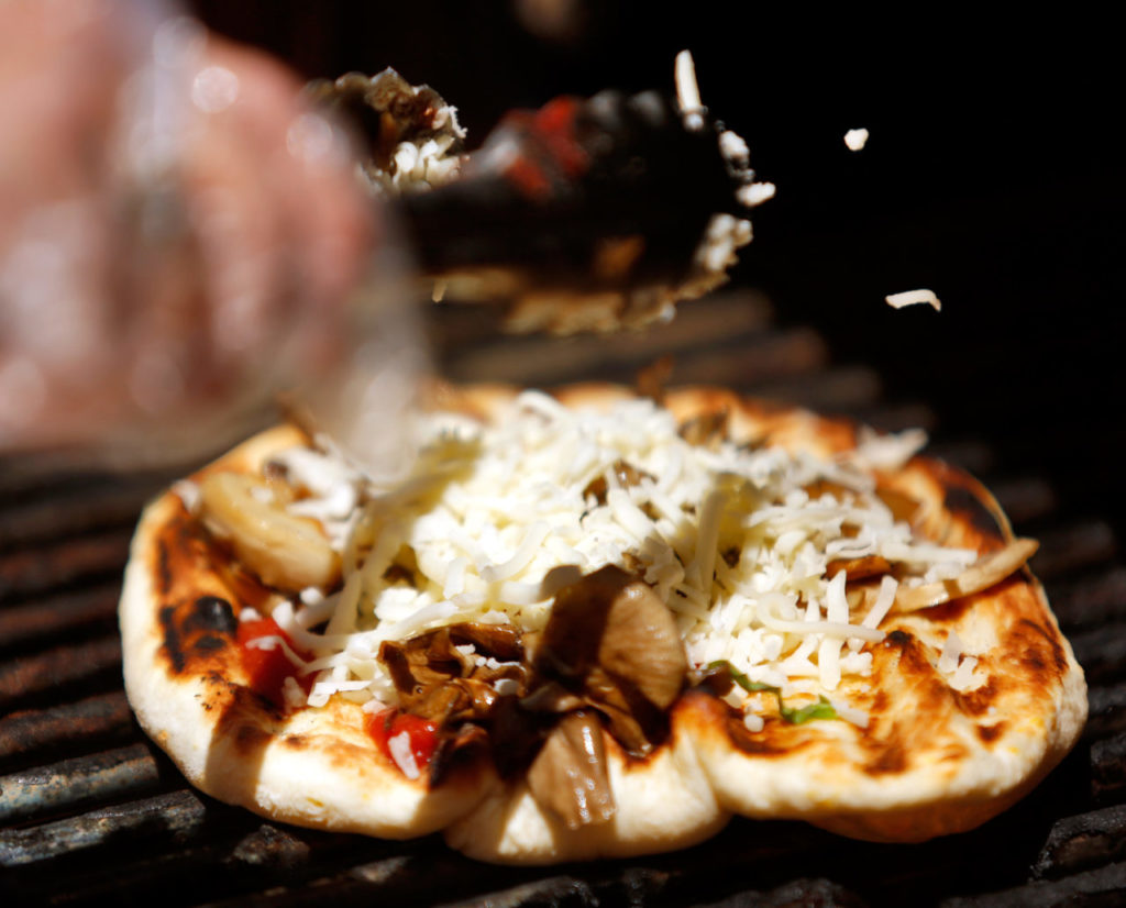 Chef John Ash and staff from Worth Our Weight restaurant help guests grill personal pizzas during the North Coast Food and Wine Festival at SOMO Village in Rohnert Park, California, on Saturday, June 10, 2017. (Alvin Jornada / The Press Democrat)