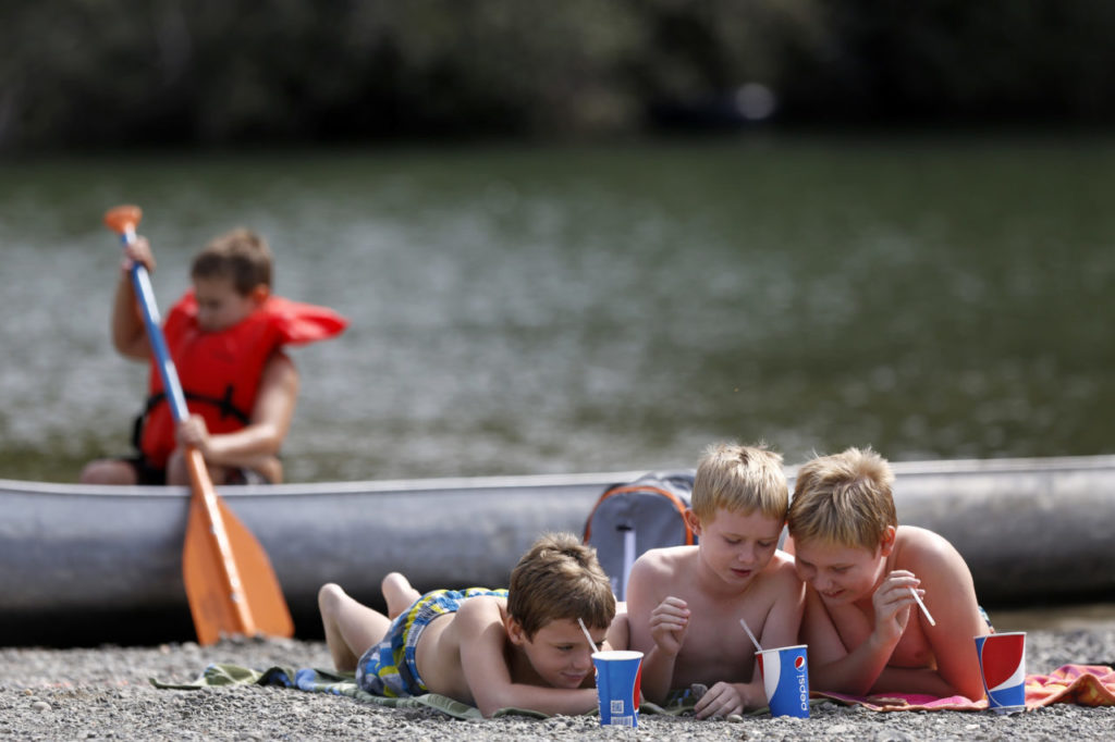 (From left) Liam McGrath, 8, Shane Murphy, 8, and his brother Emmett Murphy, 11, hang out and drink sodas at Johnson's Beach on Sunday, September 28, 2014 near Guerneville, California. (BETH SCHLANKER/ The Press Democrat)