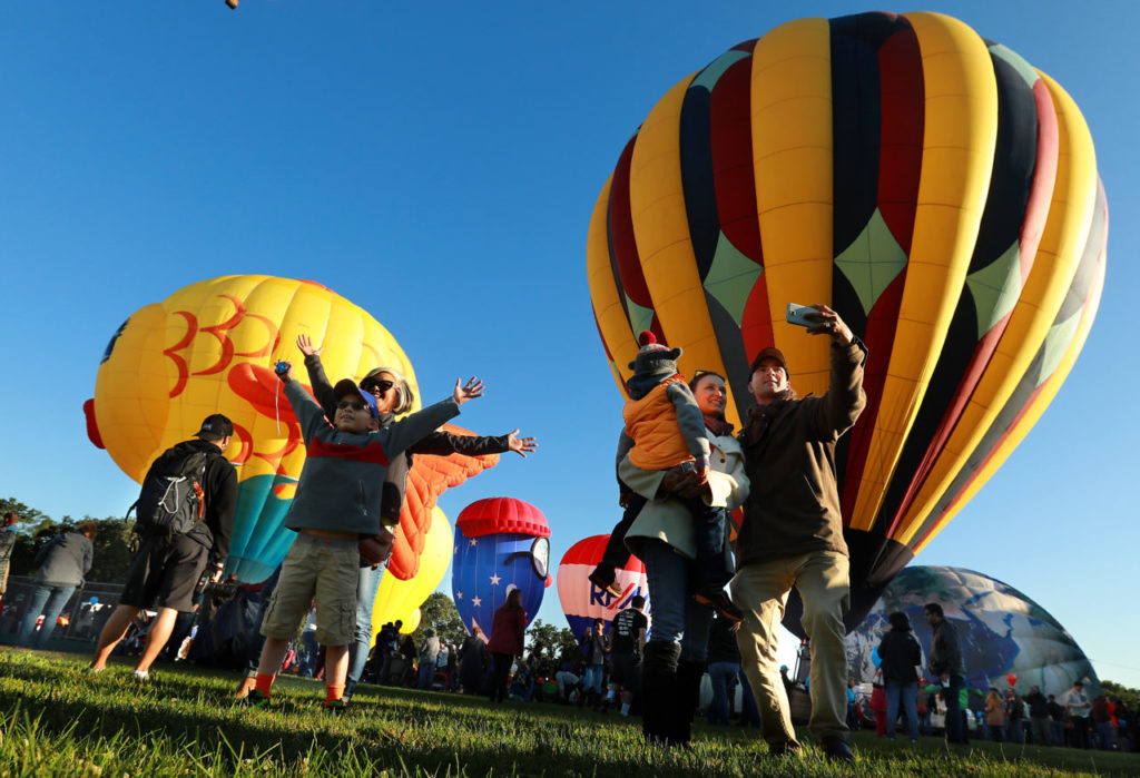Visitors take their photos in front of some of the over 30 balloons at Keiser Park in Windsor for the Sonoma County Hot Air Balloon Classic. (John Burgess/The Press Democrat)