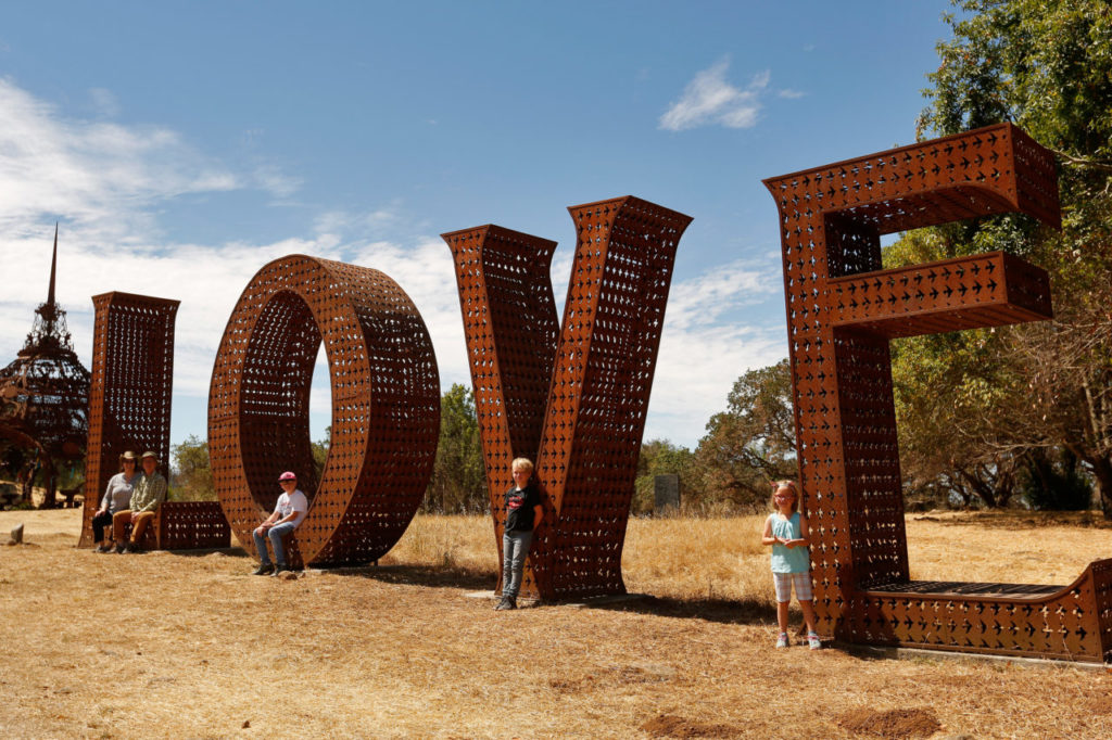 The Adler Family stands around the iconic "Love" sculpture for a photograph during the sculpture garden reopening at Paradise Ridge Winery in Santa Rosa, California, on Saturday, July 7, 2018. (Alvin Jornada / The Press Democrat)