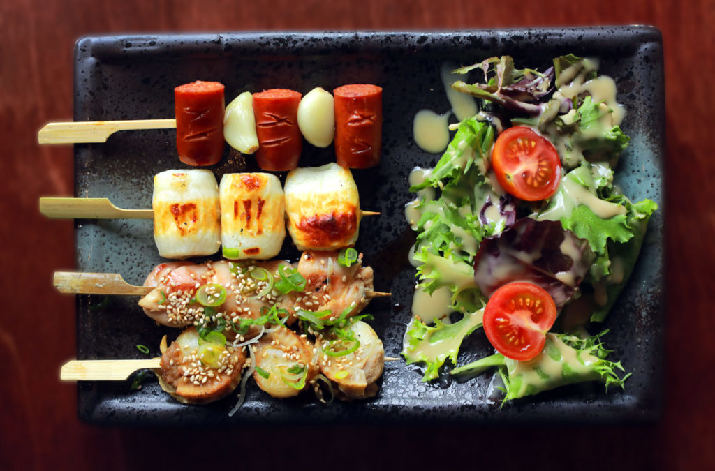 From top, Kushiyaki: Spicy Berkshire pork sausage, Chikuwa fish cake with cheese, Momo chicken thigh with tare sauce and Hotate scallops with tare sauce from Izakaya Kitaru restaurant in Petaluma. (photo by John Burgess/The Press Democrat)