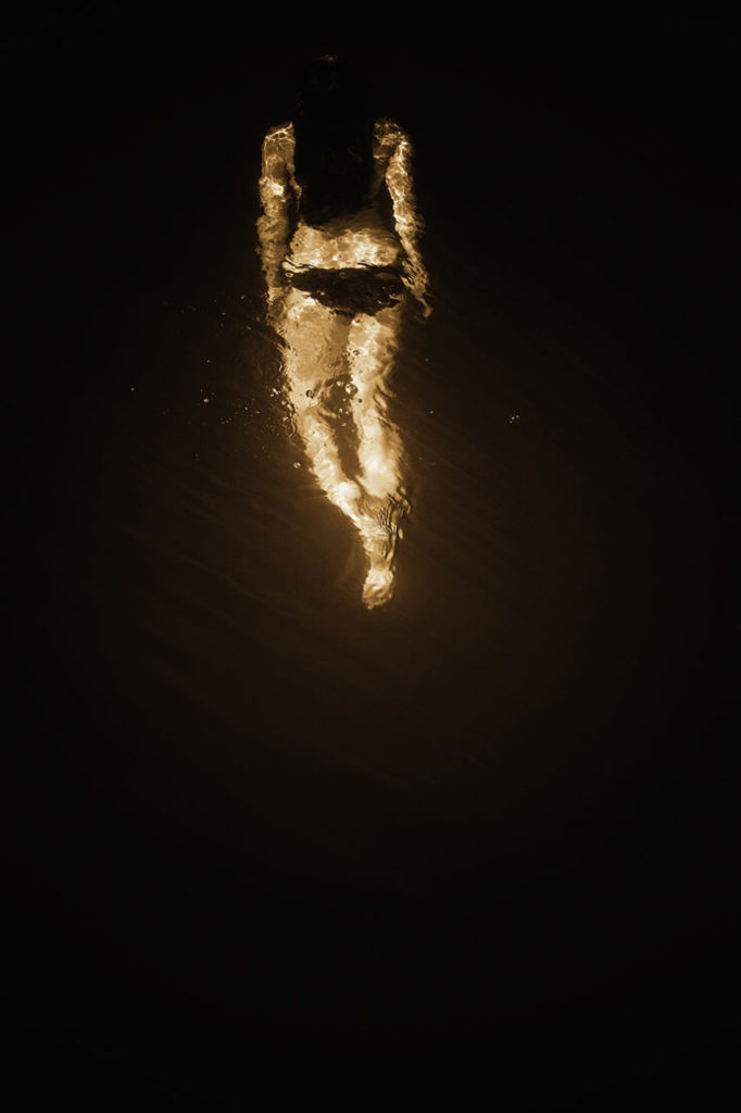 Looking down on a female swimmer under the water of the Russian River in Monte Rio, California. This image is sepia toned.