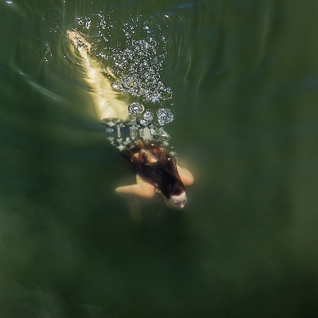 Top view of a woman swimming under water in the Russian River, Monte Rio, California.The focus on this image is soft.