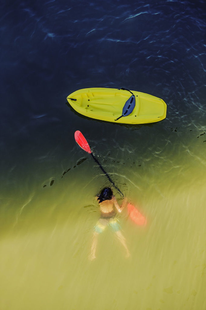 Looking down on a woman swimmping towards her kayack in the Russian River, Monte Rio, California.