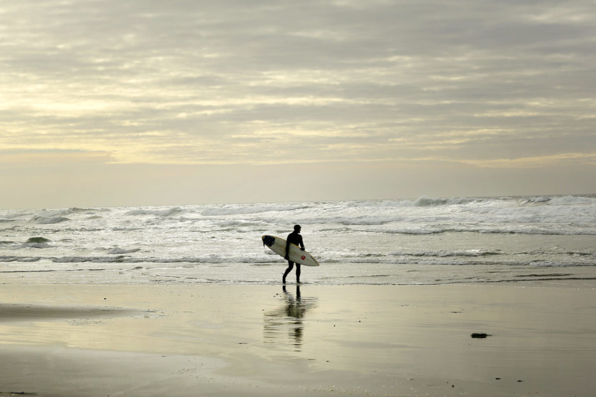 Lukas Clevenger walks along the beach at Salmon Creek looking for any rideable waves. (Conner Jay/For Sonoma Magazine)