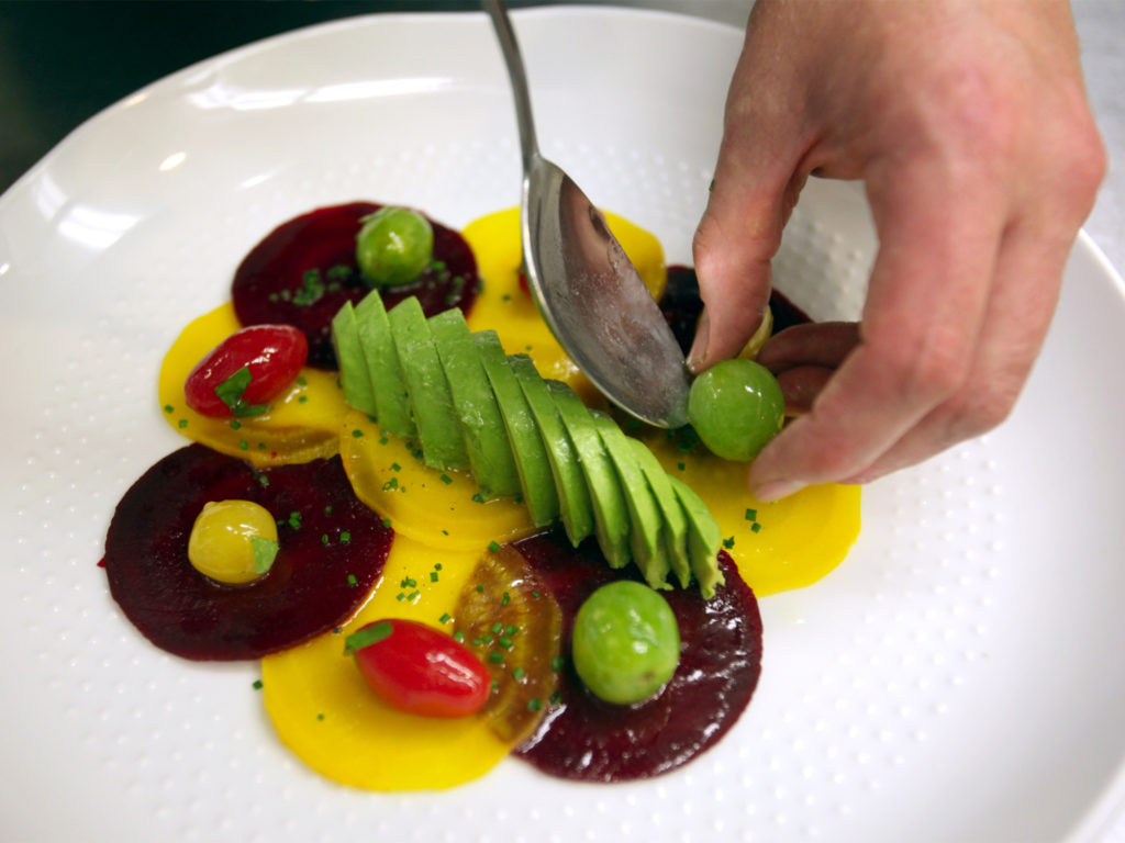 Ryan Fancher, chef of Barndiva, prepares a dish that includes beets, heirloom tomatos, garlic, artichokes, tempura green beans, fava beans carrots and a basil oil.