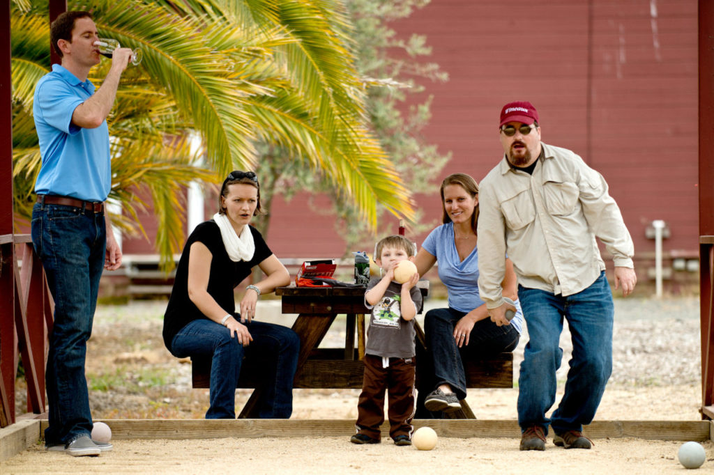 Jay McCarthy, right, lines up his next throw with his three-year-old son, Eddie, while Kira Plaine, Monika McCarthy and Dan Plaine look on, at the bocce ball court outside Kokomo Winery in Healdsburg, Calif., on April 6, 2013. (Alvin Jornada / The Press Democrat)
