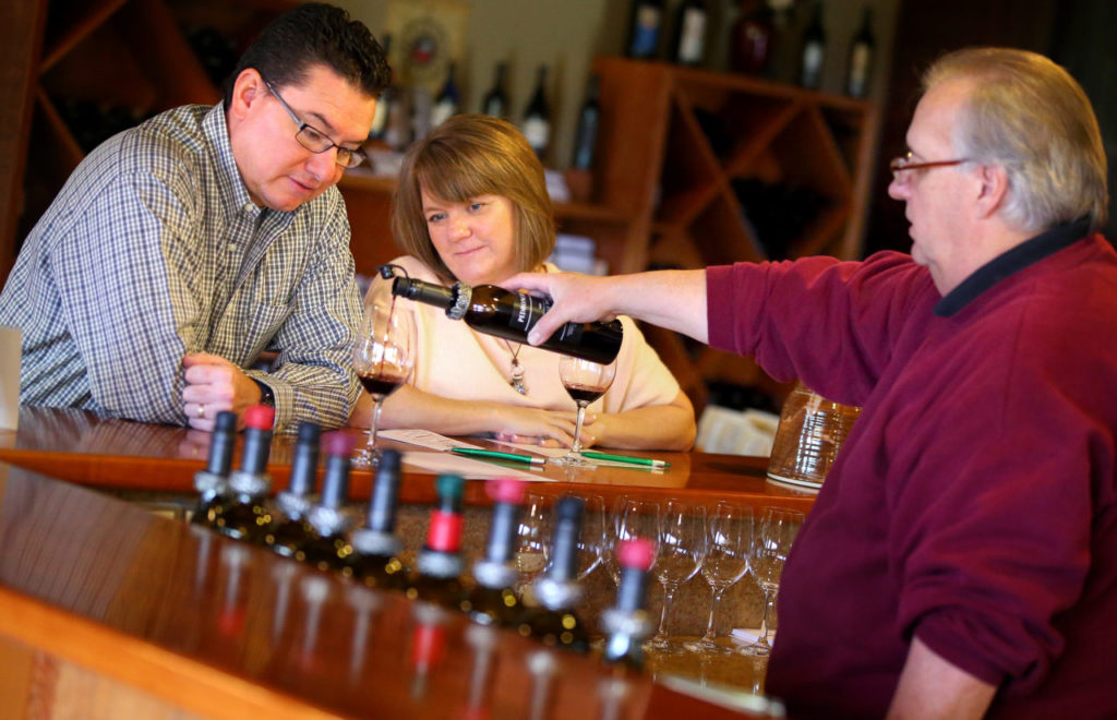 Tasting room manager Gary Gross, right, pours a 2009 Vintage Port for Bernadette and Eduardo Gamez, from Chandler, Arizona, at Pedroncelli Winery, in Geyserville on Thursday, November 13, 2014. (Christopher Chung/ The Press Democrat)