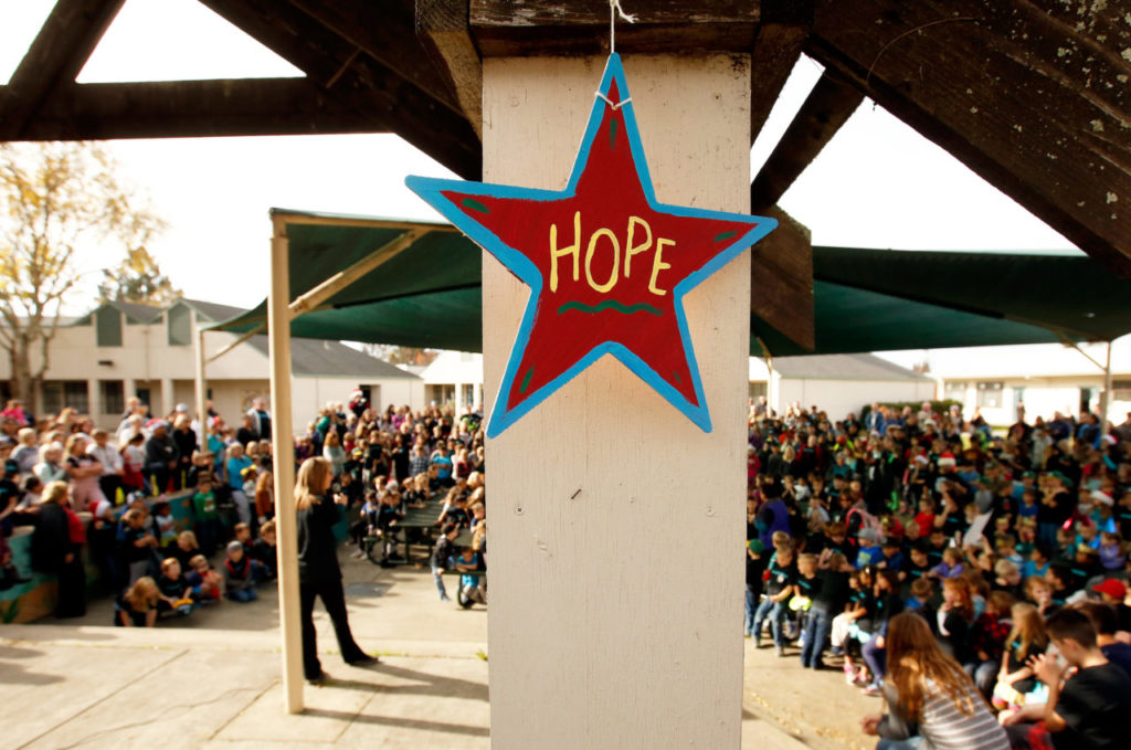 An ornament hangs from courtyard awning while principal Patty Dineen, at left, welcomes students back to John B. Riebli Elementary School for the first time since the Tubbs Fire damaged the school and decimated the Larkfield-Wikiup neighborhood around it, in Santa Rosa, California on Friday, December 22, 2017. (Alvin Jornada / The Press Democrat)