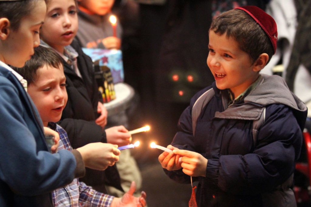 Zalman Wolvovsky, right, shares his candlelight with his brothers Avremi and Shalom, and friend Mendel Tenenbaum during a menorah lighting ceremony for Hannukah, in Sonoma on Sunday, December 9, 2012. (Christopher Chung/ The Press Democrat)