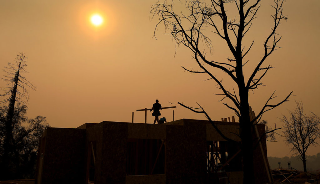 Tsiyani Escort, left, and Greg Pettegrew put work on a home that was razed during the 2017 Tubbs fire on Fairway Knoll Court in Santa Rosa's Fountaingrove, as the skies are mired in smoke from the Camp fire in Butte County, Thursday, Oct. 8, 2018. (Kent Porter / The Press Democrat) 2018