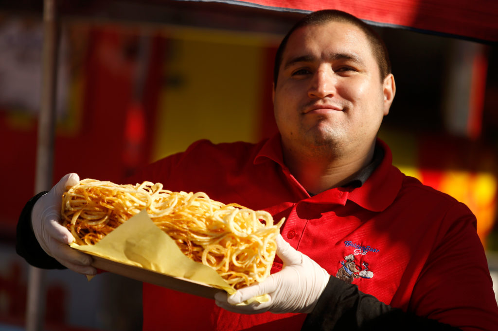 Martin Pulido holds up an order of giant curly fries during the first day of the Sonoma-Marin Fair, in Petaluma, California, on Wednesday, June 20, 2018. (Alvin Jornada / The Press Democrat)