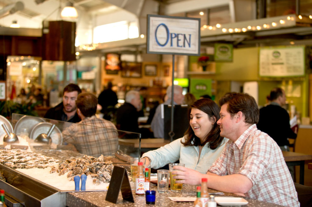 Bryan Kays, right, and Noelle Shamroukh enjoy drinks at Hog Island Oyster Company inside Oxbow Public Market in Napa, Calif., on January 8, 2014. (Alvin Jornada / The Press Democrat)