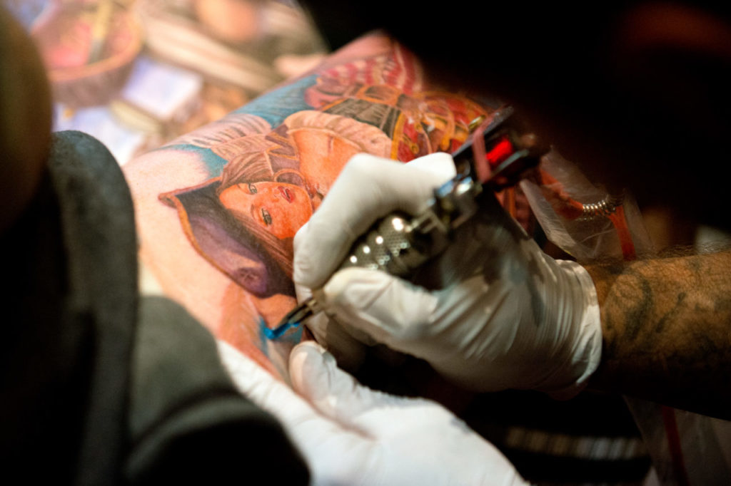 Angel Gallardo of American Classic Tattoo adds a shade of blue to a tattoo on a client's thigh during Izzy's 23rd annual Santa Rosa Tattoos and Blues in Santa Rosa, Calif., on March 1, 2014. (Alvin Jornada / The Press Democrat)