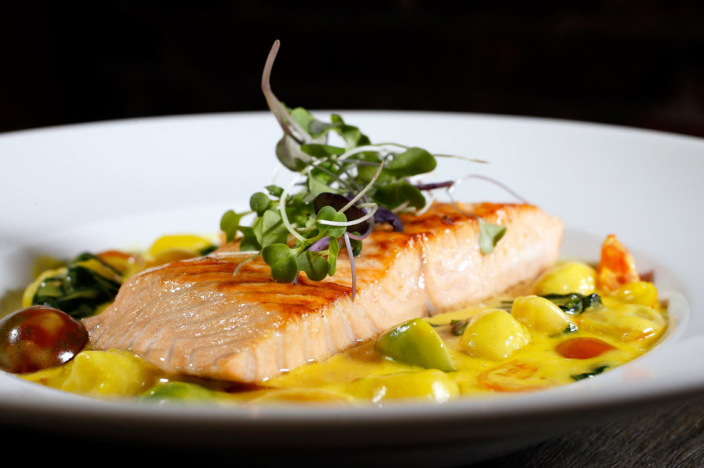 Wild king salmon with saffron sauce, Bloomsdale spinach, artichoke hearts, toy box cherry tomatoes over gnocchi at 256 North in Petaluma. (Alvin Jornada/The Press Democrat)