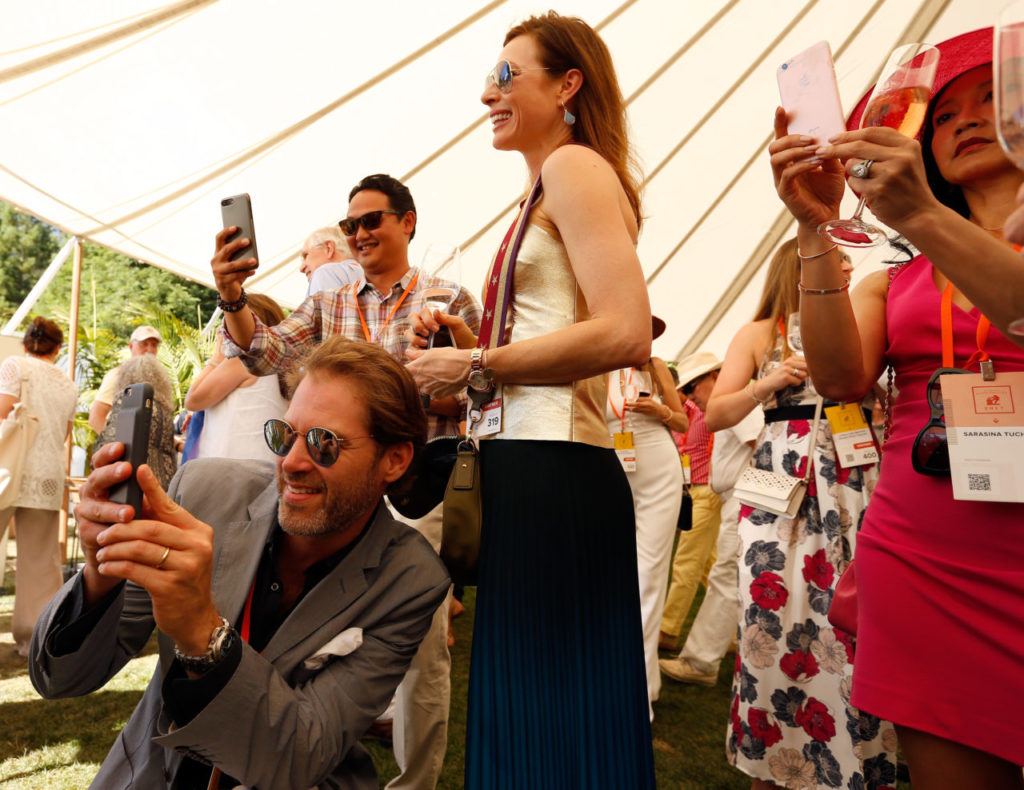 Oscar Henquet, lower left, and Denise Henquet pause with other guests to snap photos of a rare Balthazar, 12-liter bottle, of 2014 Screaming Eagle cabernet sauvignon during Auction Napa Valley at Meadowood Resort in St. Helena, California on Saturday, June 3, 2017. (Alvin Jornada / The Press Democrat)