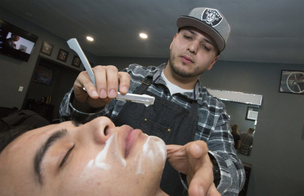 Mario Carreno gets a straight-razor shave from Barbers Garage proprietor Jose Alvarez. (Photo by Robbi Pengelly/Index-Tribune)