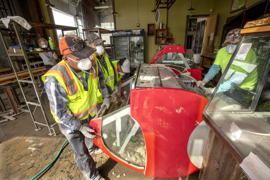 Workers try to upright a cold case tipped over in last week's flooding in the Village Bakery in the Barlow business district in Sebastopol on Monday. (photo by John Burgess/The Press Democrat)