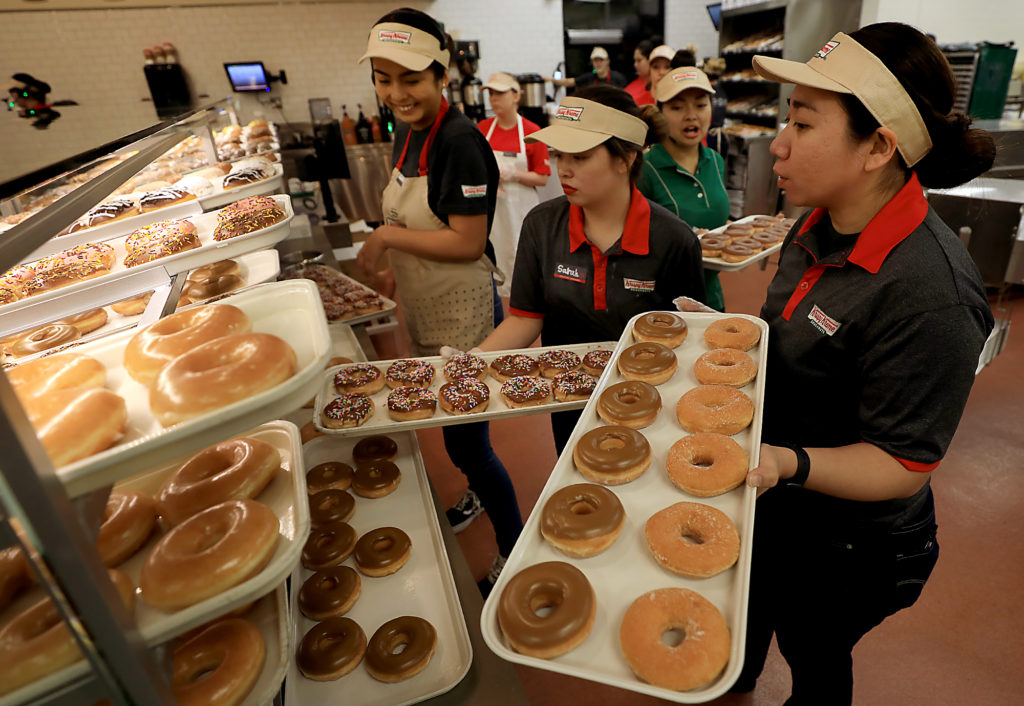 Employees stock the display case prior to the grand opening of the Krispy Kreme in Rohnert Park, Tuesday, Nov. 6, 2018. (Kent Porter / The Press Democrat) 2018