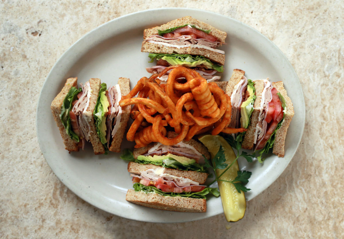 The Club Sandwich with avocado and seasoned curly fries from Mac's Deli in downtown Santa Rosa. (John Burgess/The Press Democrat)