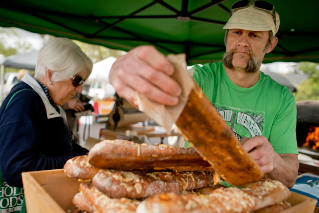 The Bejkr, Mike Zakowski selects a stecca baguette for a customer at the Sonoma Farmers Market in Sonoma, Calif., on April 4, 2014. (Alvin Jornada / The Press Democrat)